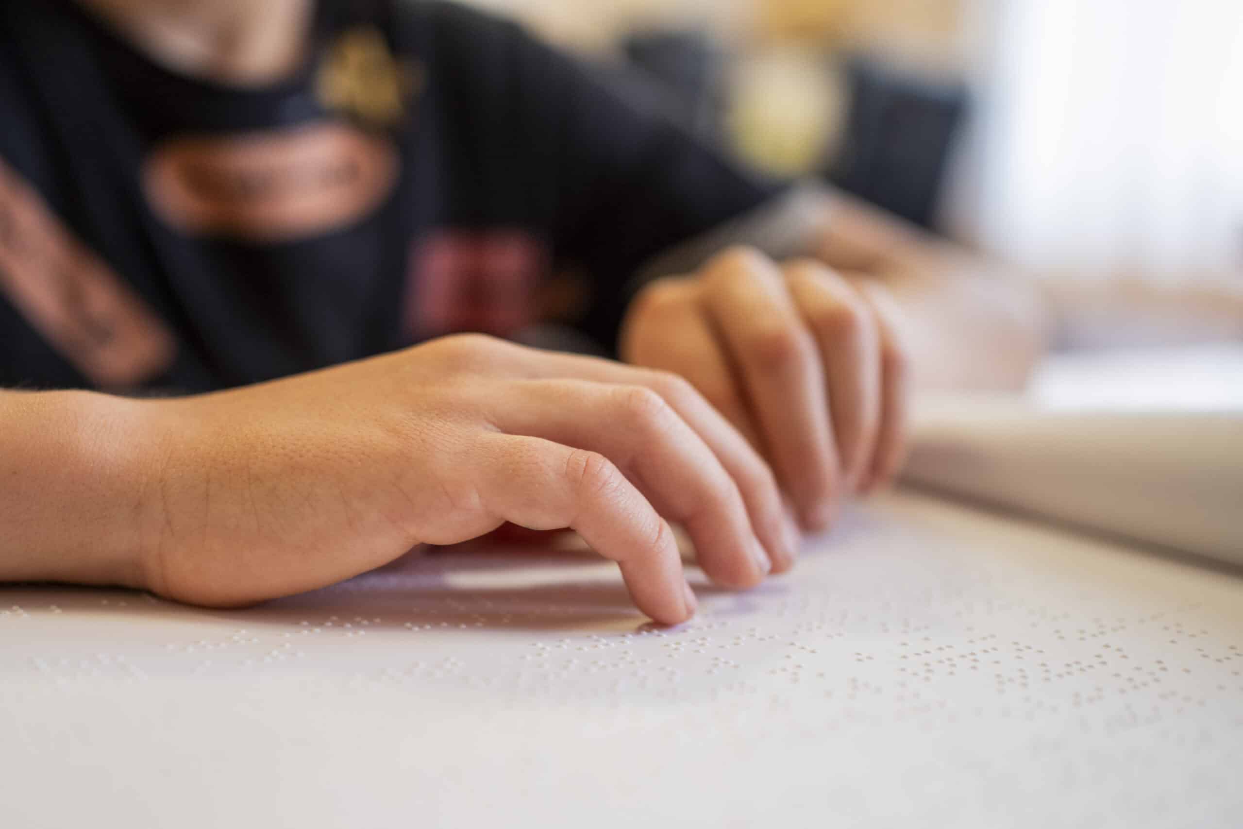 un ragazzo legge con le dita un libro in braille