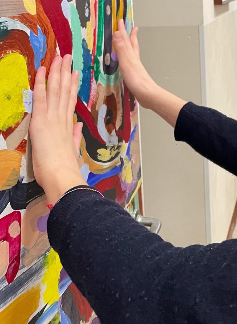 Le mani di una donna esplorano una delle opere colorate esposte lungo il corridoio del liceo Duca d'Aosta di Padova